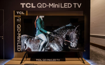 TCL 115QM7K TV on a stand at a CES 2025 showcase.