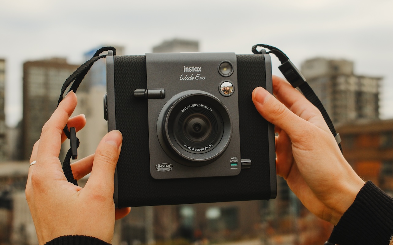 Des mains plient l'Instax WIDE Evo de Fujifilm 