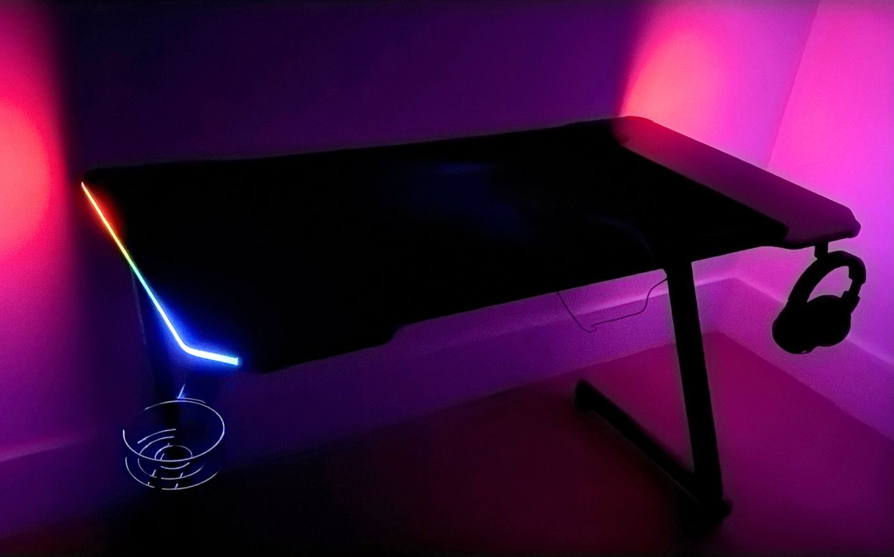 The IMGadgets Z-Shaped Gaming Desk in a dark room with the LED lights.