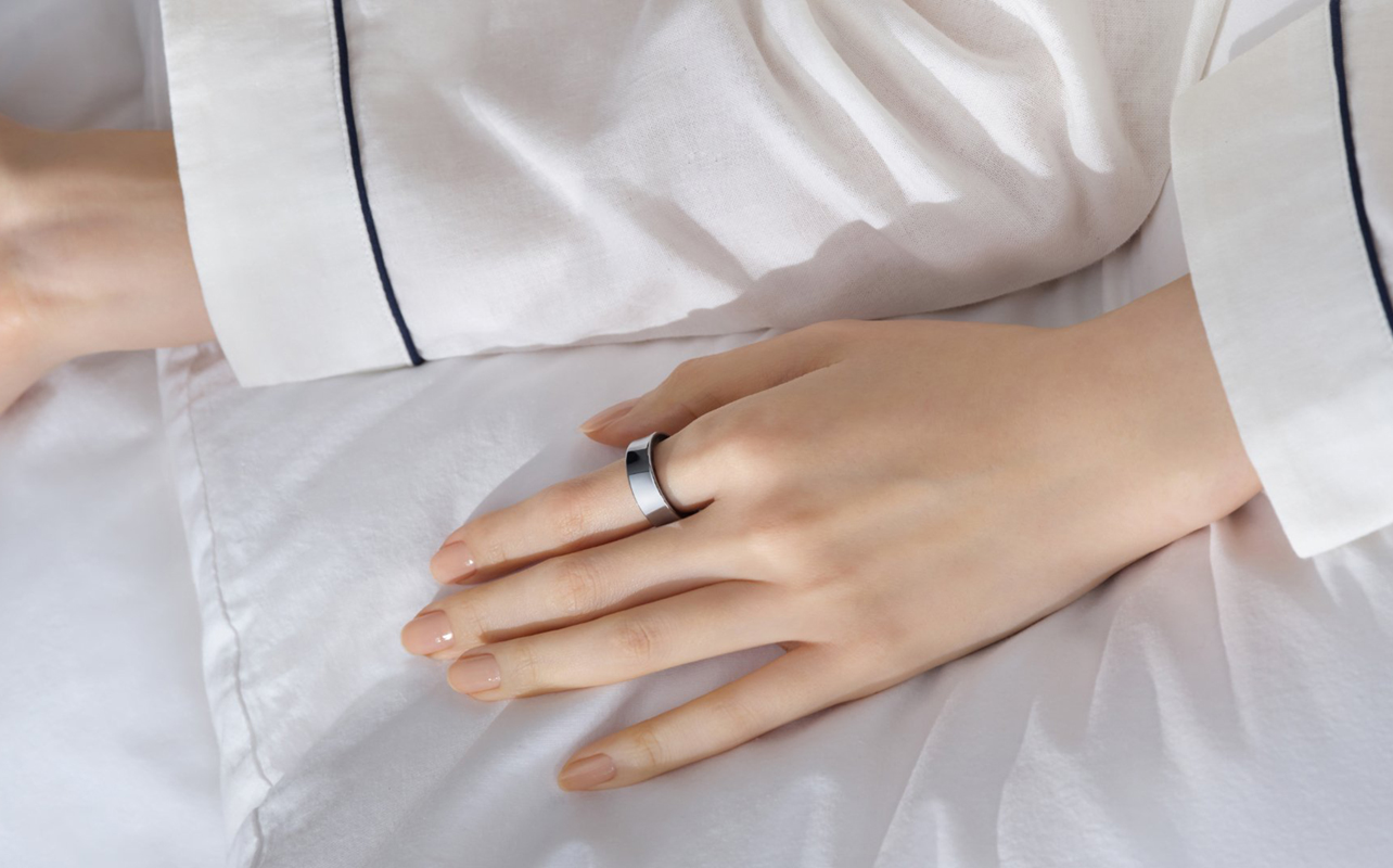 Samsung Galaxy Ring on left index finger laying in bed.