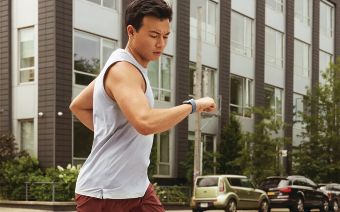 A man running and looking at his smartwatch.