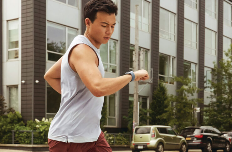 A man running and looking at his smartwatch.