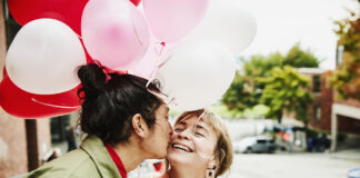 Man Kissing Smiling Girlfriend On Cheek While Giving Her Balloons During Date on Valentines day