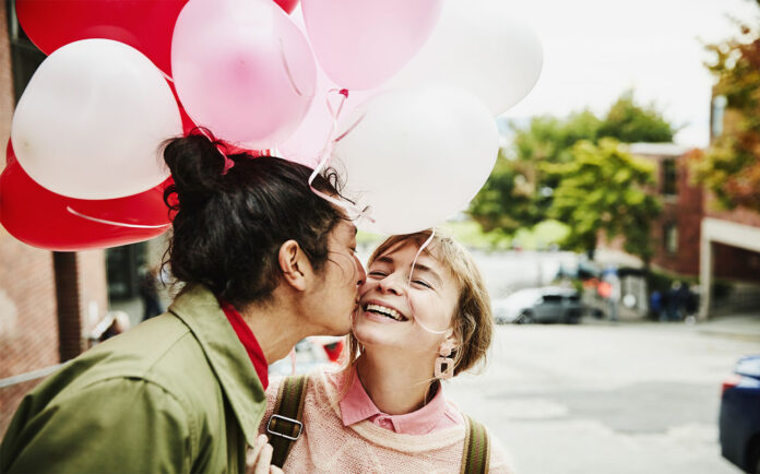 Man Kissing Smiling Girlfriend On Cheek While Giving Her Balloons During Date on Valentines day