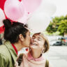 Man Kissing Smiling Girlfriend On Cheek While Giving Her Balloons During Date on Valentines day