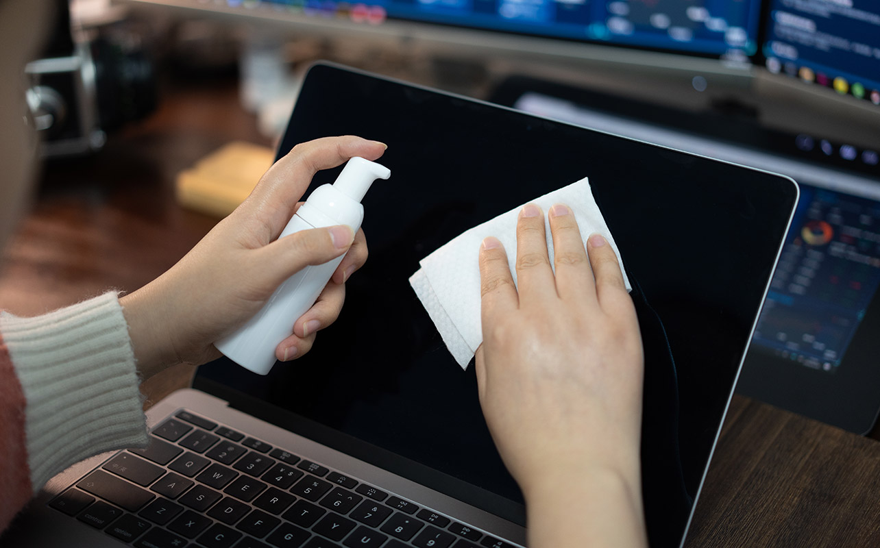 Young woman wiping down laptop screen