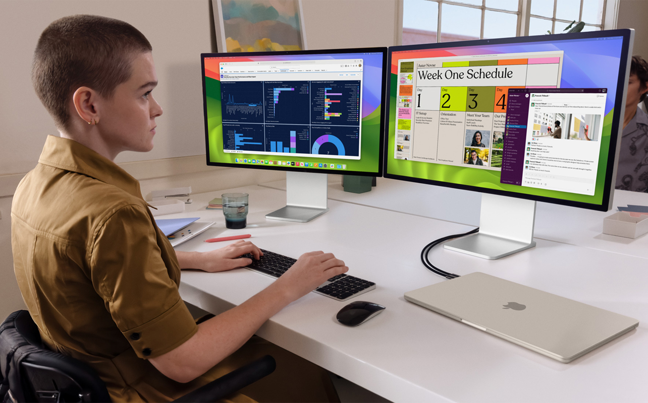 A worker at a desk running two monitors from a closed MacBook Air.