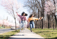 Portrait of the two friends enjoying walk together surrounded by blooming flowers