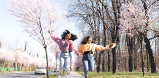 Portrait of the two friends enjoying walk together surrounded by blooming flowers