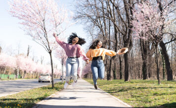 Portrait of the two friends enjoying walk together surrounded by blooming flowers