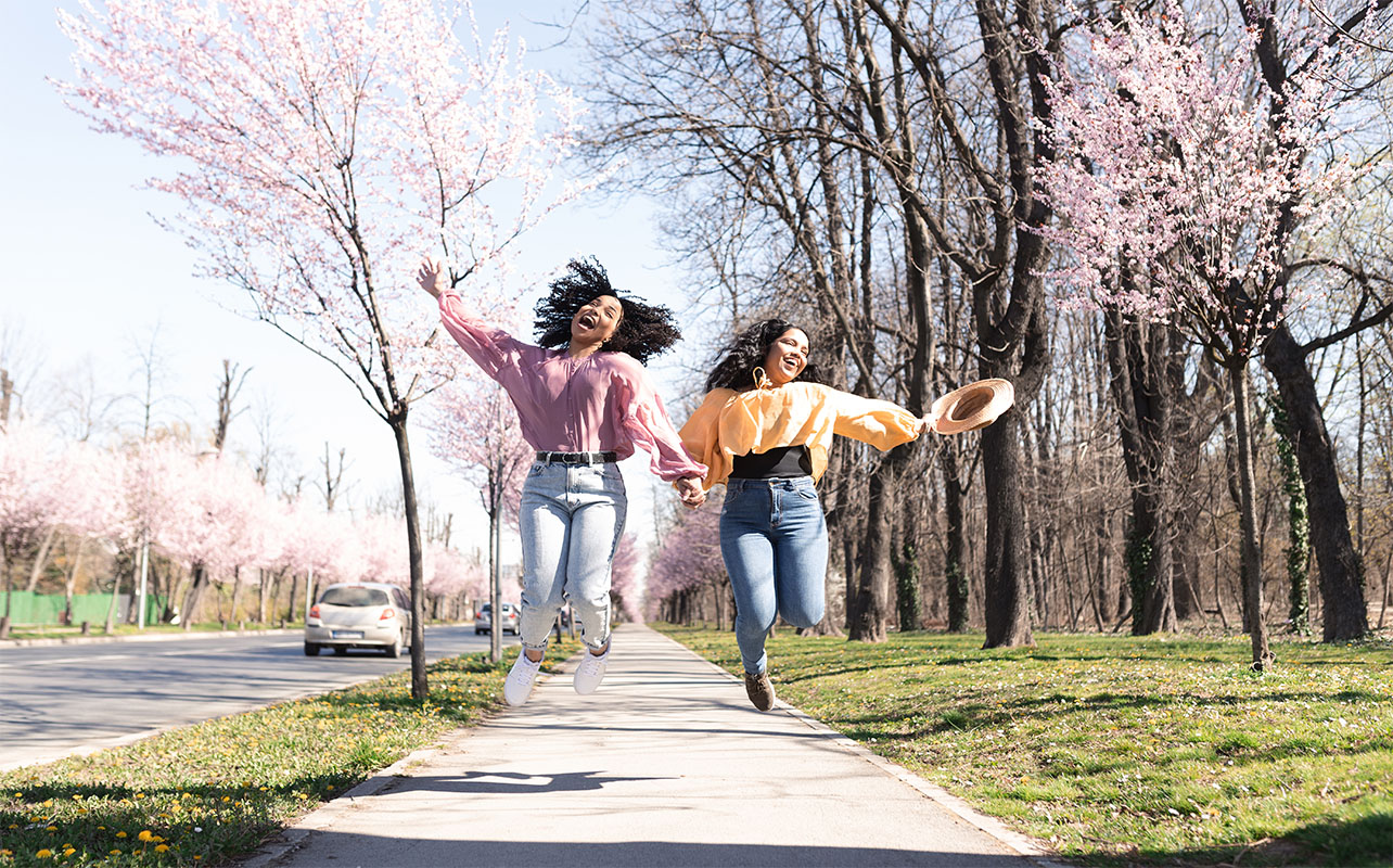 Portrait of the two friends enjoying walk together surrounded by blooming flowers