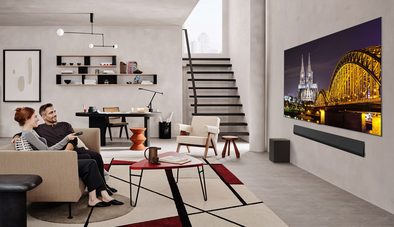 Couple assis sur le canapé regardant la télévision sur un téléviseur DELO evo de LG au salon.