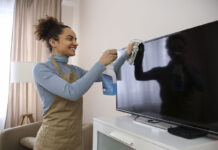 Woman cleaning her TV screen with a microfibre cloth.