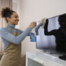 Woman cleaning her TV screen with a microfibre cloth.