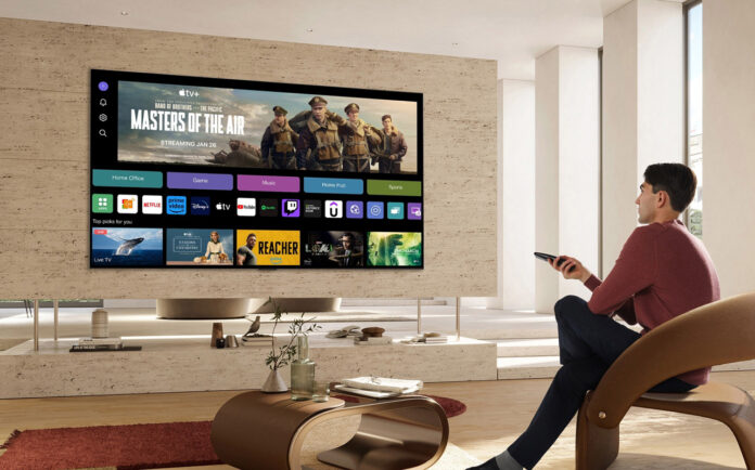 Man watching TV with smart TV interface onscreen.