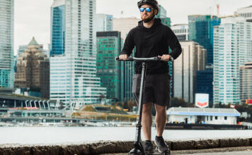 A man rising the Apollo City electric scooter by the water and smiling.