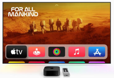 An Apple TV 4K in front of a big screen showing the interface.