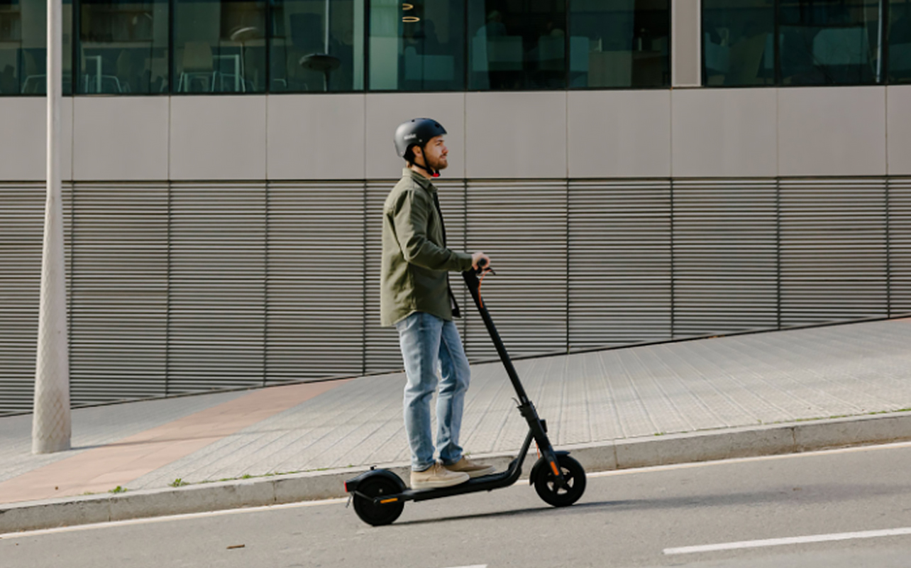 A person rides an electric scooter wearing a helmet as proper e-scooter accessory.