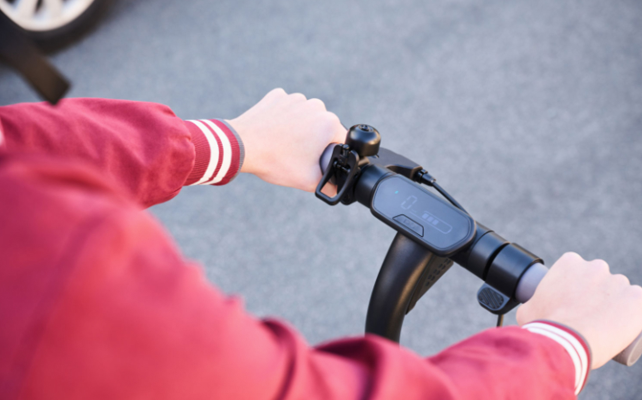 Le guidon d'une trottinette électrique avec un écran affichant des informations sur la conduite et la batterie.