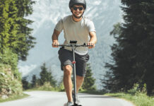 A man riding an iScooter i9 electric scooter and smiling.