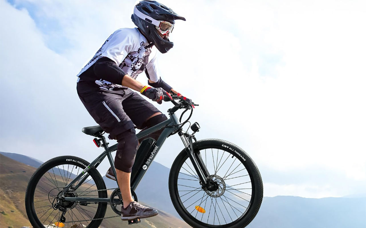 A man atop a hill on an Isinwheel M10 e-bike with a serious helmet.