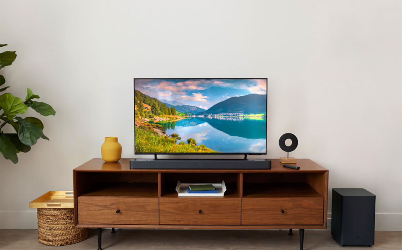 A JBL Deep Bass soundbar on a stand with a TV above it.