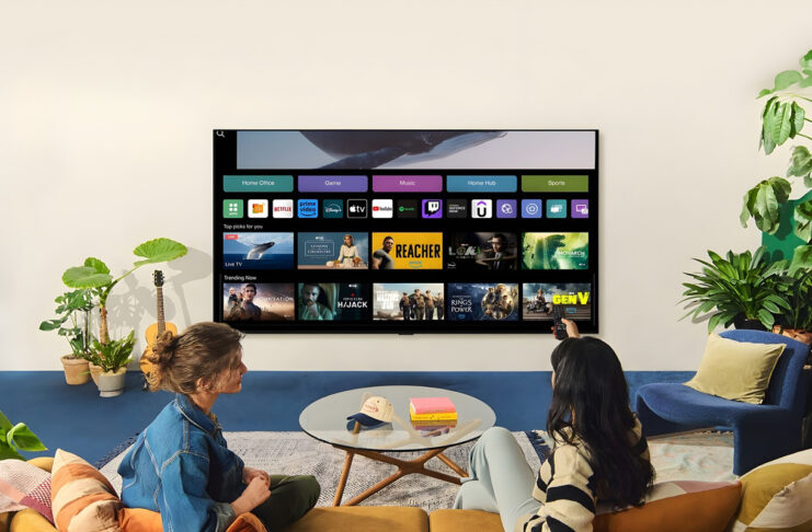 Two women watching an LG TV in a living room with one holding a remote.