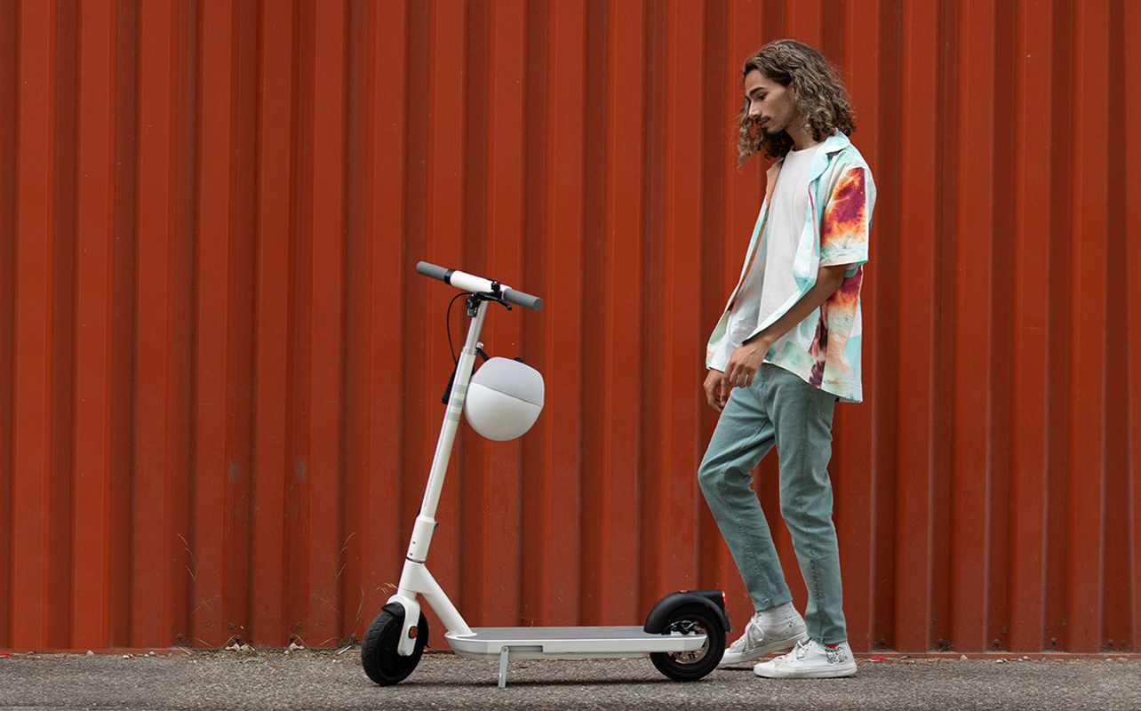 A man standing beside the Okai ES10 electric scooter.