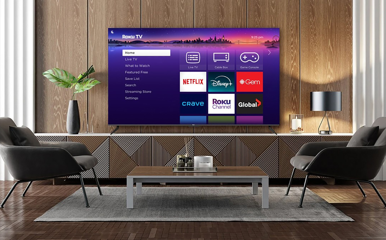 A Roku TV in a living room set-up with a table and two chairs in front.