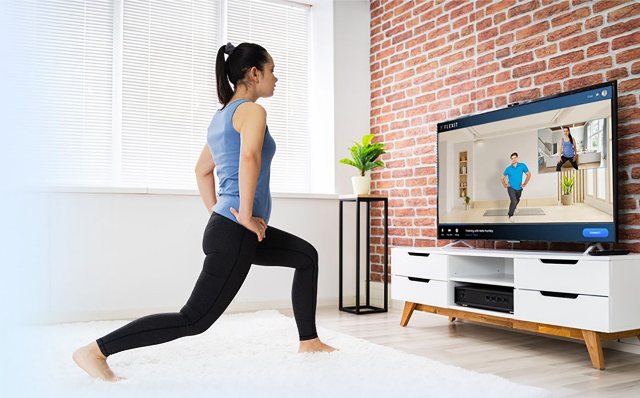 Une femme qui suit un entraînement sur un téléviseur intelligent moderne de Samsung. 