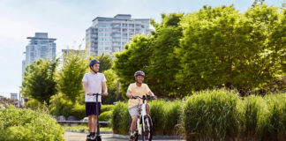 Two people riding a Segway Ninebot e-bike and e-scooter down a sunny road.