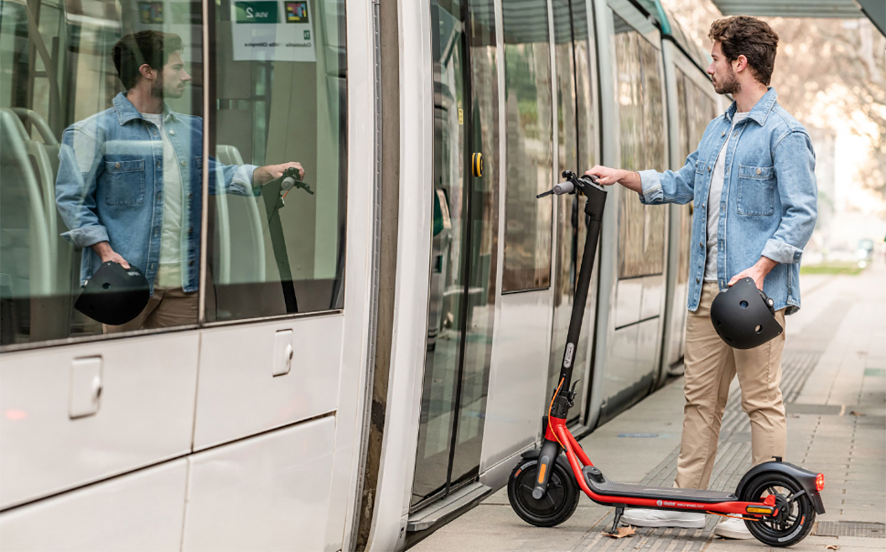 A man entering a subway with a Segway Ninebot e-scooter.