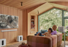 Two people watching TV with a Sonos Arc sound bar mounted underneath.