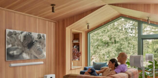 Two people watching TV with a Sonos Arc sound bar mounted underneath.