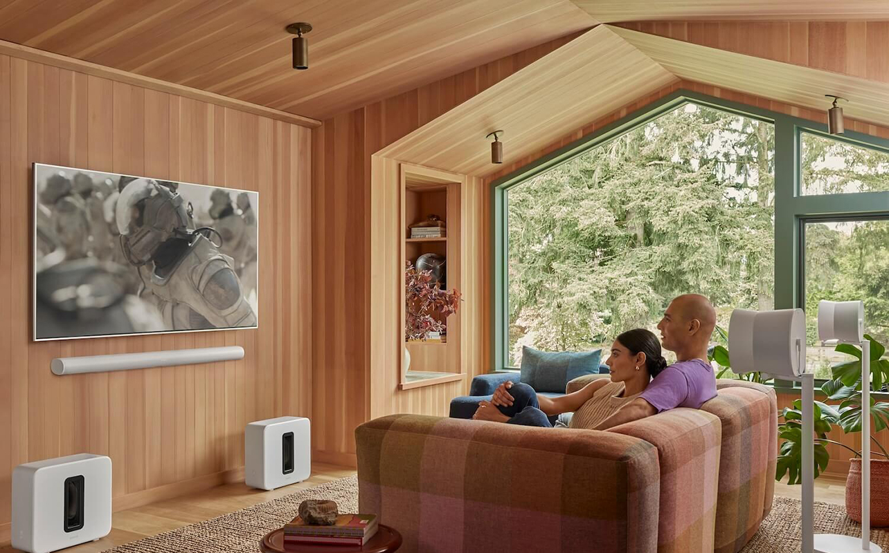 Two people watching TV with a Sonos Arc sound bar mounted underneath.
