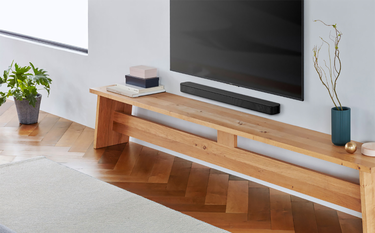 A Sony HTS100F sound bar mounted under a TV with a piece of furniture underneath.