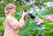 Woman taking photo of flower with macro lens.