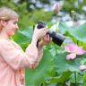 Woman taking photo of flower with macro lens.