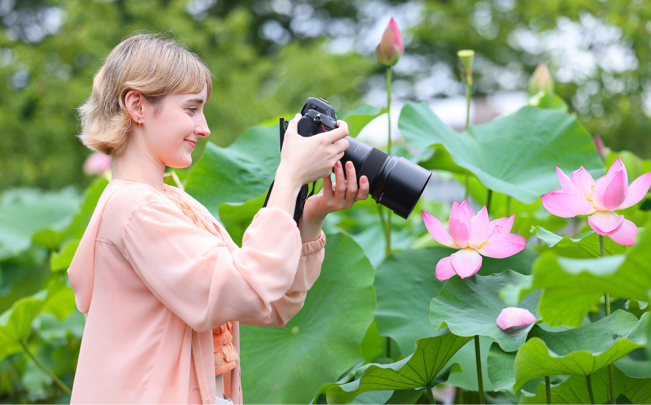 Woman taking photo of flower with macro lens.
