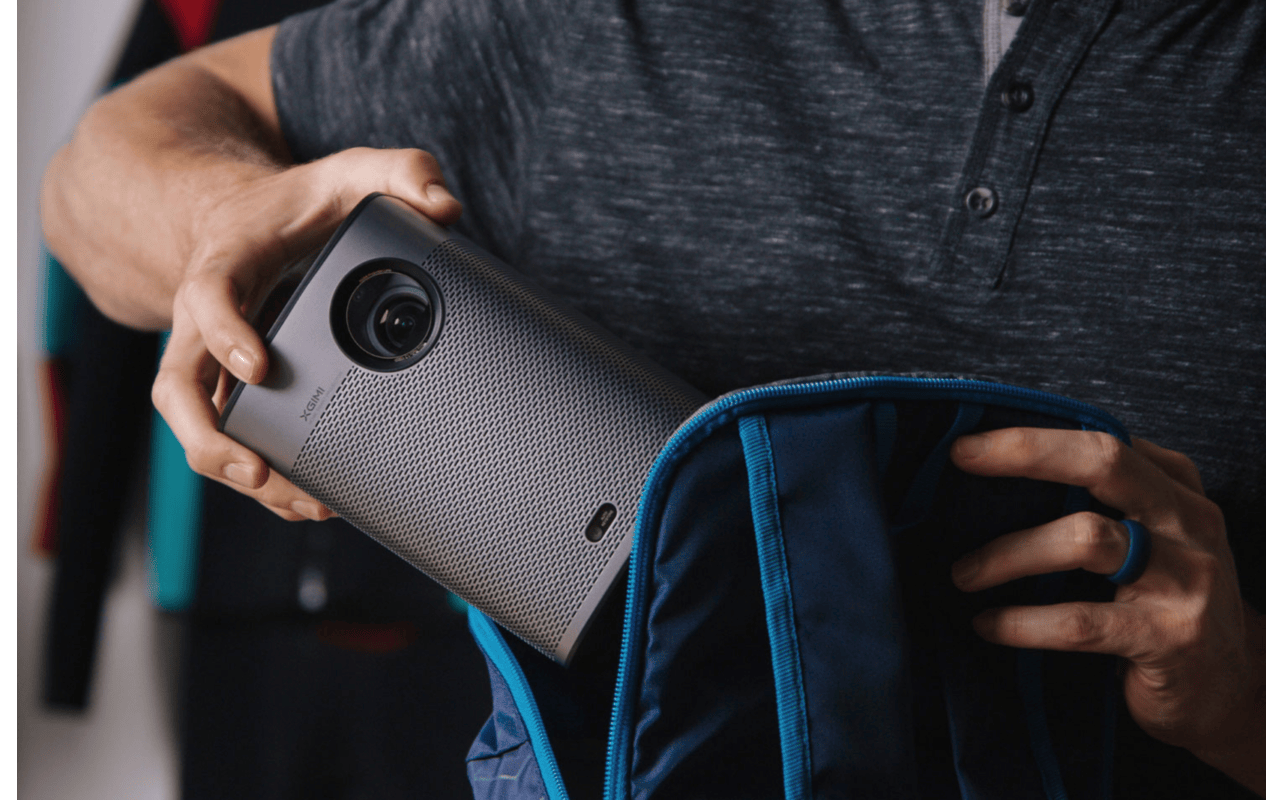 A portable projector being put into a backpack.