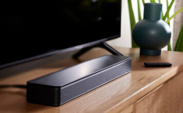 Small soundbar sitting in front of TV on entertainment unit.