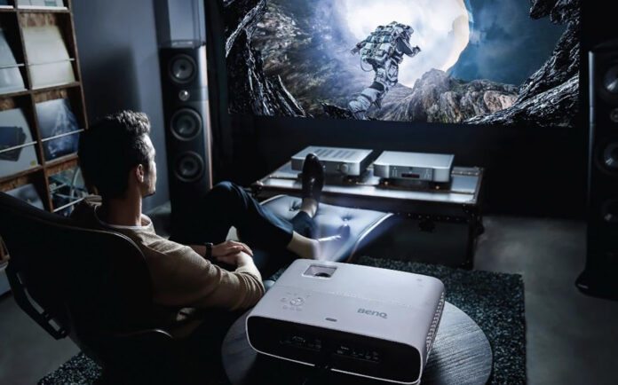 A man sitting back playing games with a BenQ projector.