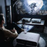 A man sitting back playing games with a BenQ projector.