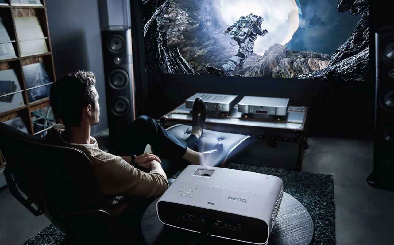 A man sitting back playing games with a BenQ projector.