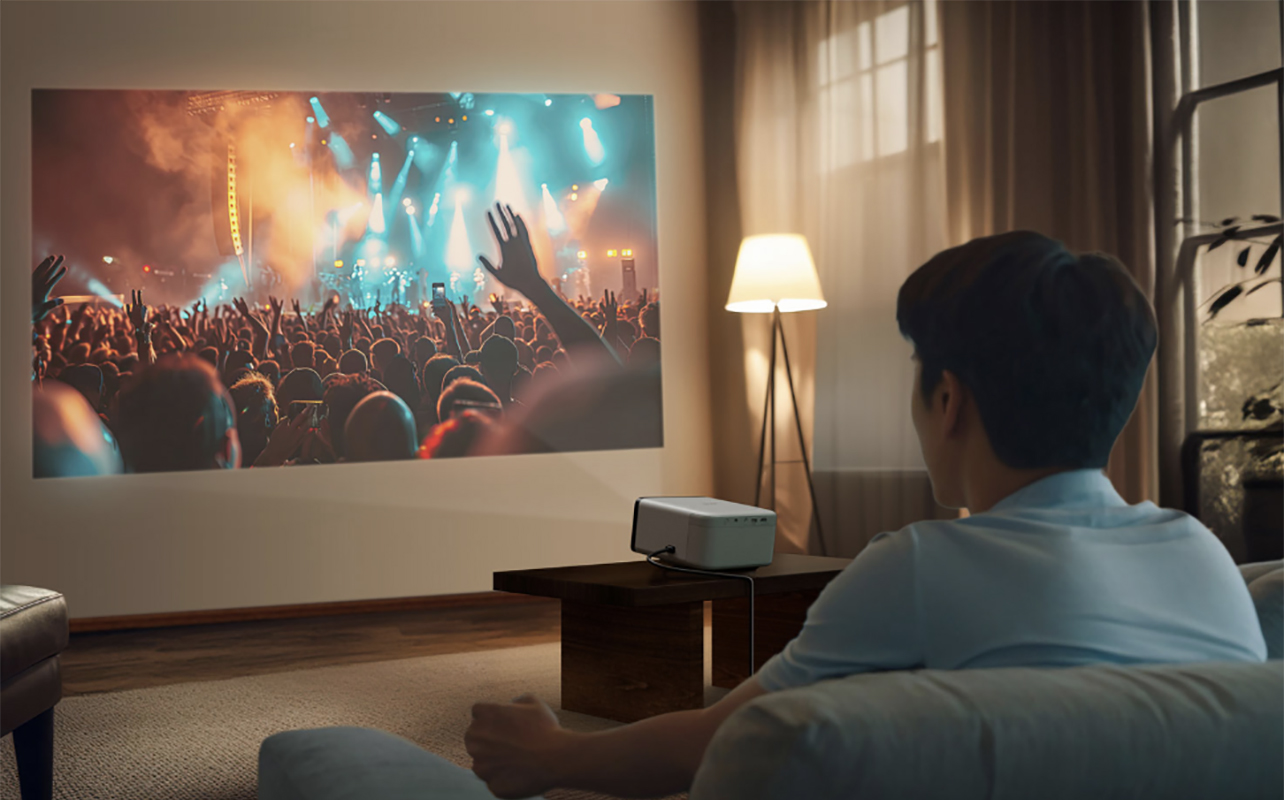 Un homme assis regarde un film sur un écran à l'aide du projecteur Epiqvision Mini EF21 d'Epson.