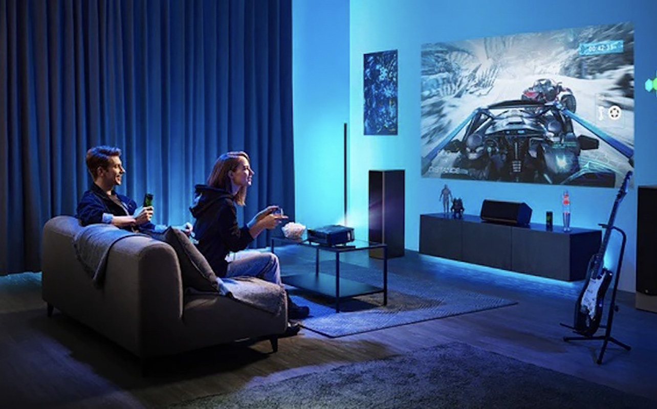 Two people in a dark room playing on a gaming projector