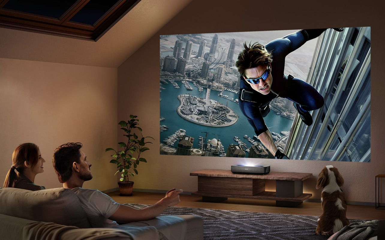 A man and woman watching a large screen from a Hisense PL2 laser projector