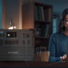 A woman working on her laptop at home in the dark with the Pion portable power station.