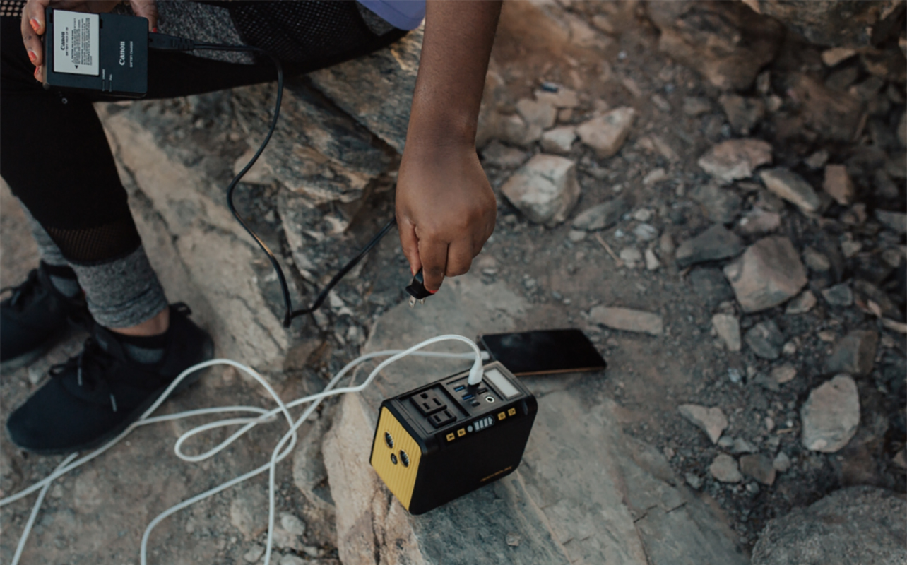 A man sitting on rocks with the Rocksolar portable power station.