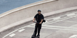 A man zooming down a road on a Segway Max G3 electric scooter